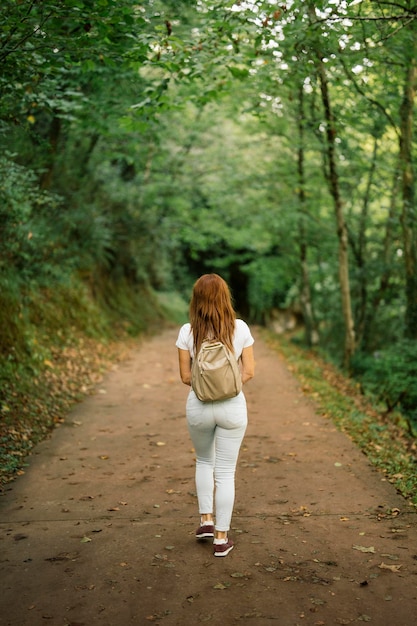 숲 한가운데 비포장도로를 걷는 여자