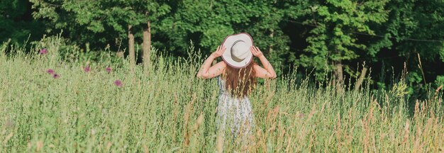 Женщина, идущая в поле в летний солнечный день, вид сзади баннер и копией пространства
