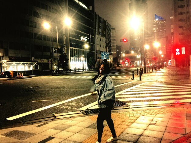 Photo woman walking on footpath in city at night