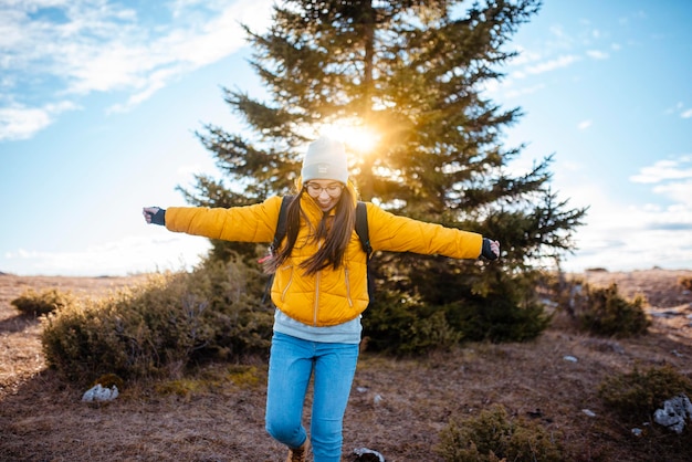 Woman walking on a hill holding a trekking pole Woman wearing jacket and backpack on a trekking expedition