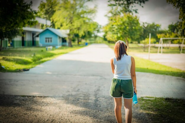 写真 手に水のボトルを持って公園を歩いている女性医療コンセプト