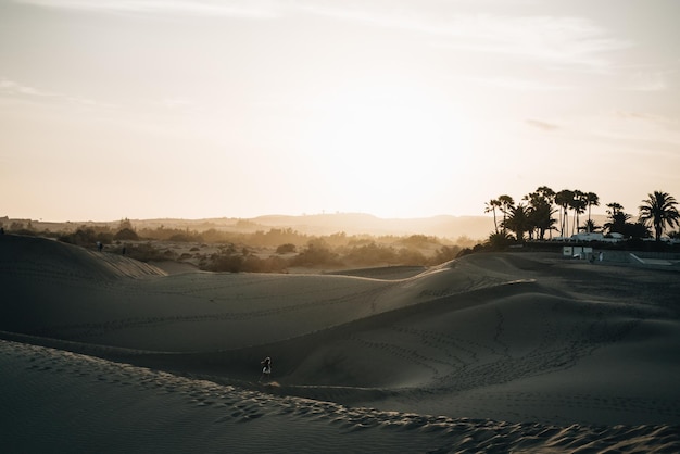 Woman walking in the middle of the desert at sunset