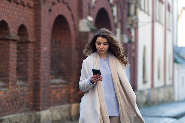 woman walking in a new city with a phone in her hands and a suitcase