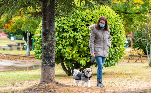 雨の中で犬と一緒に公園を歩いている女性