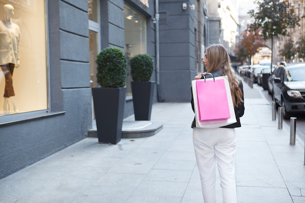 woman walking past fashion store in the city, looking at retail display, copy space