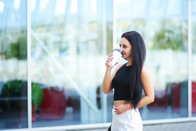 コーヒーを飲みながら通りを歩いている女性