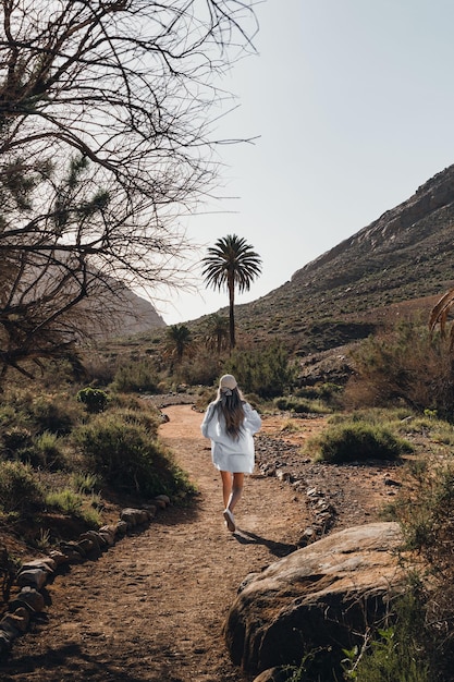 Woman walking through sand road in the middle of the nature and mountains