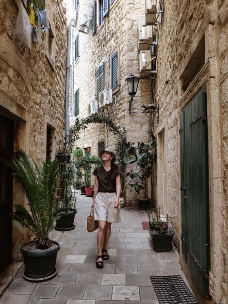 Woman walking in tiny street with stone buildings in old town Kotor Montenegro