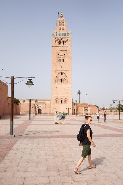 Woman walking on town square against building in city