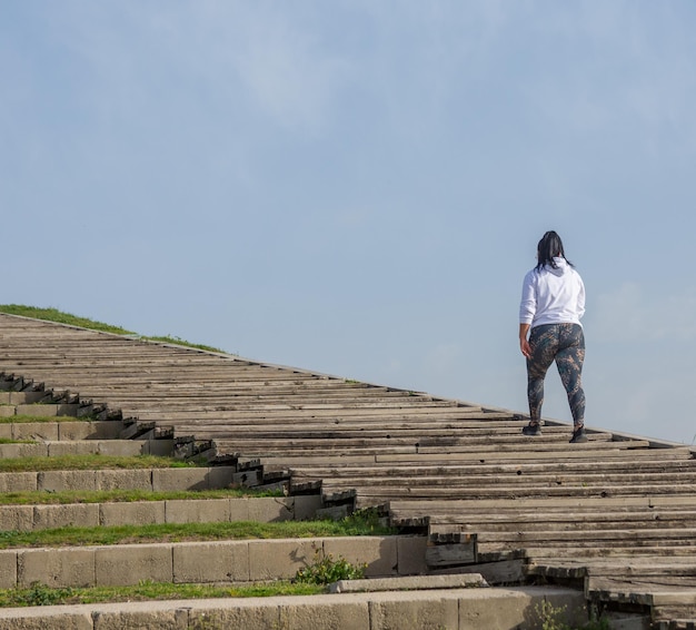 a woman walking up some stairs with a white shirt on