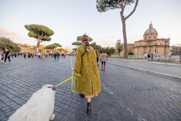 ローマの有名な中央通りを犬と一緒に歩く女性