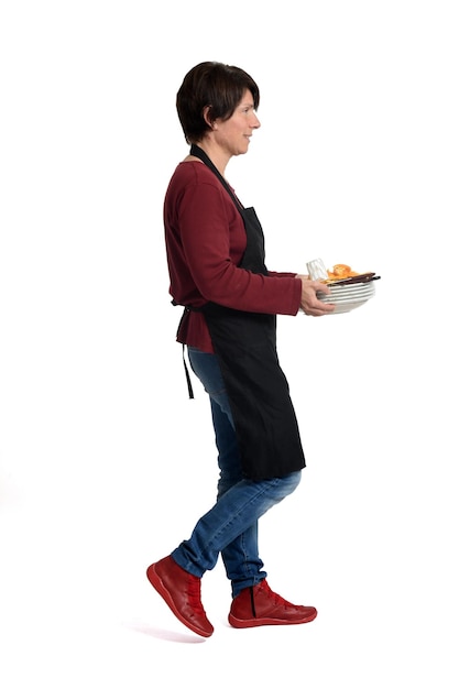 Woman walking with holding a pile of dirty plates with food on white background