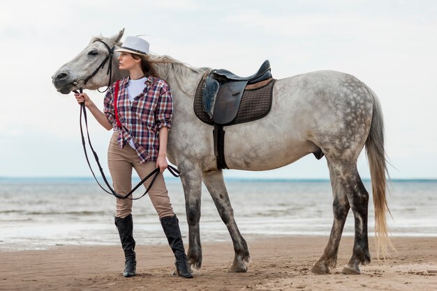 Donna che cammina con un cavallo sulla spiaggia