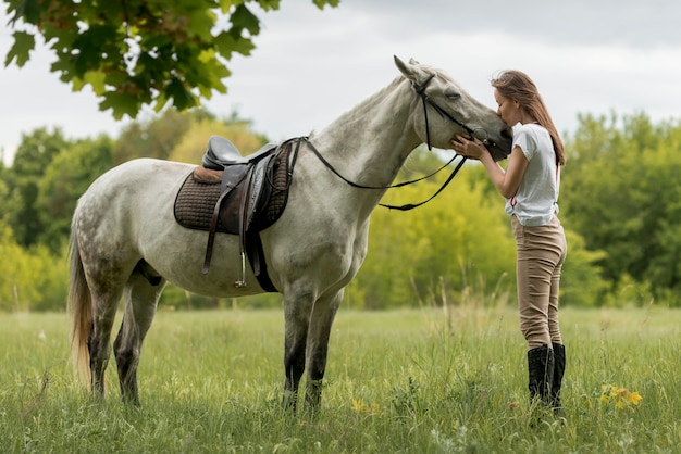 Foto donna che cammina con un cavallo in campagna