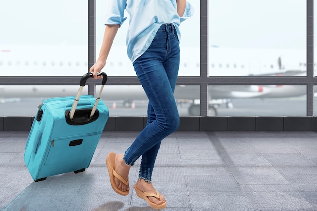 The woman walking with a suitcase on the airport terminal