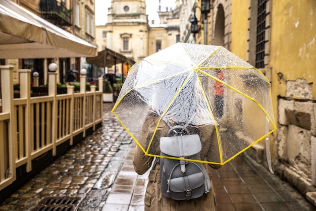 写真 雨の下で透明な傘で歩いている女性