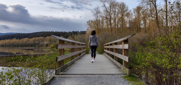 Woman Walking on a Wooden Path with green trees in Shoreline Trail