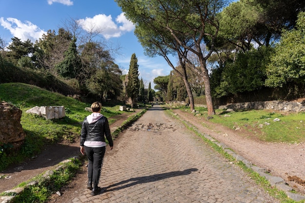 A woman walks down a cobblestone road in a park