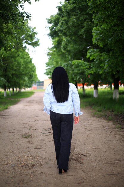 Photo a woman walks down a dirt road in a forest.
