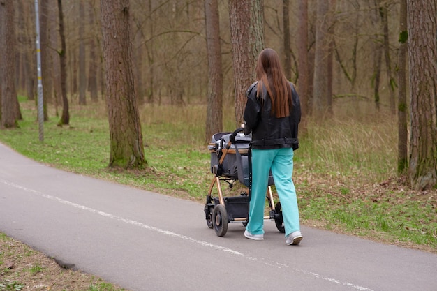 A woman walks down a road with a walker.