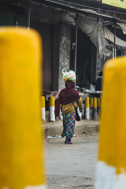 Photo a woman walks down a street with a large bag on her head.