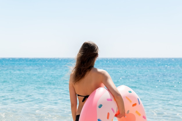 여자가 바닷물에 들어갑니다. 해변에서 풍선 반지에 편안한 소녀입니다. 여름 방학 및 휴가 개념.