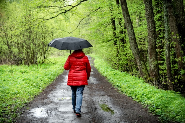 Foto la donna cammina nel parco sotto un ombrello sotto la pioggia