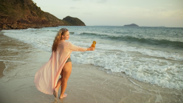 Woman walks on sunset on beach against background of sea Girl i