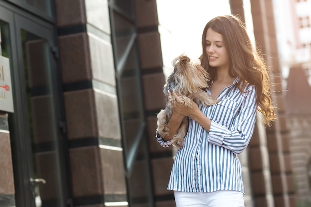 女性は街で犬と一緒に歩きます。