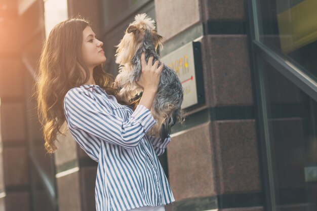 女性は街で犬と一緒に歩きます。