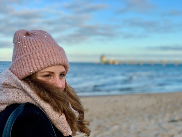 Foto donna con abiti caldi in spiaggia in inverno