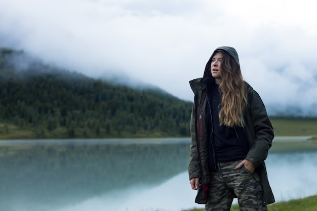 A woman in warm clothes near lake covered with thick fog