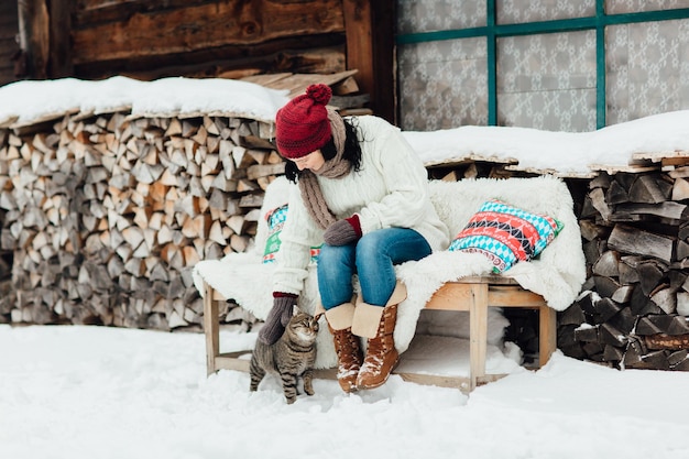 woman in warm clothing with cat sitting on bench