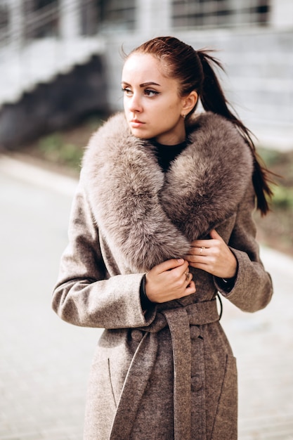 屋外の毛皮を持つ暖かいコートを着た女性