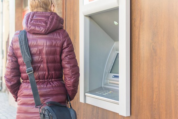 ATMの前で暖かいジャケットを着た女性