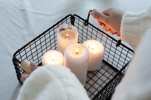 Woman in warm white winter sweater standing at the kitchen at home lighting up the candles