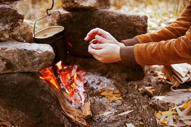 Woman warming hands near the outdoor fire in the nature