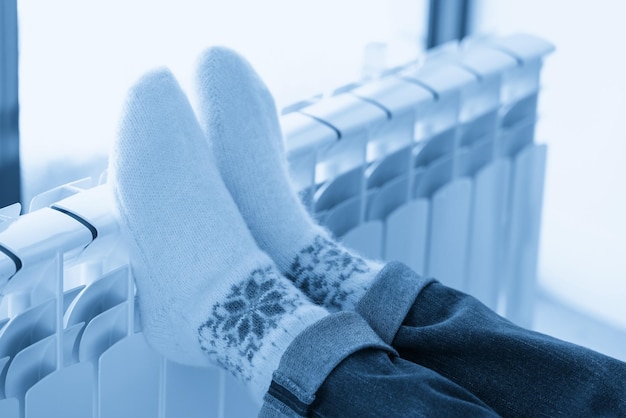 Woman warming up with feet on heater wearing woolen socks