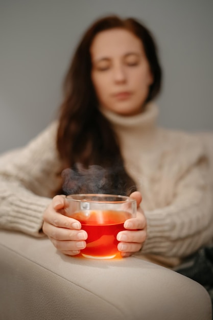 A woman warms her hands on mug of tea after a walk