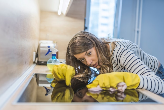 Foto donna lavare e pulire piano cottura elettrico a casa cucina