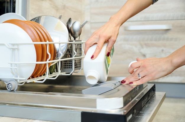 The woman washes the  dishes in the dishwashing machine.