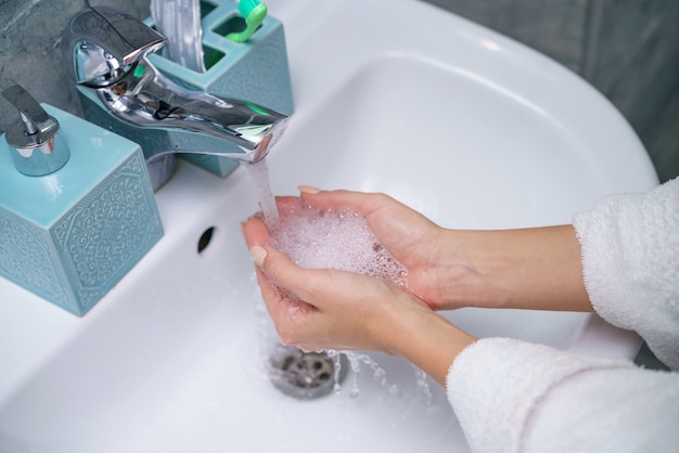 La donna si lava la mano nel lavandino del bagno