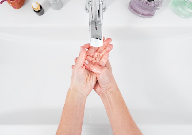 Woman washes her hands under a water tap. Hygiene concept, top view, healthcare. Personal hygiene and body care