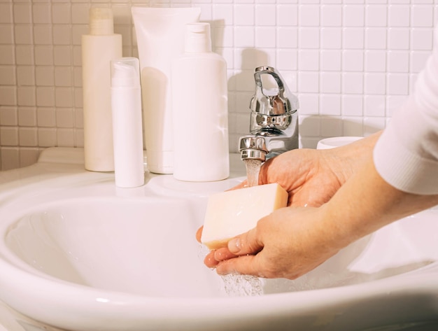 Woman washes her hands with soap over sink in bathroom Hygiene and health cleanliness and body care