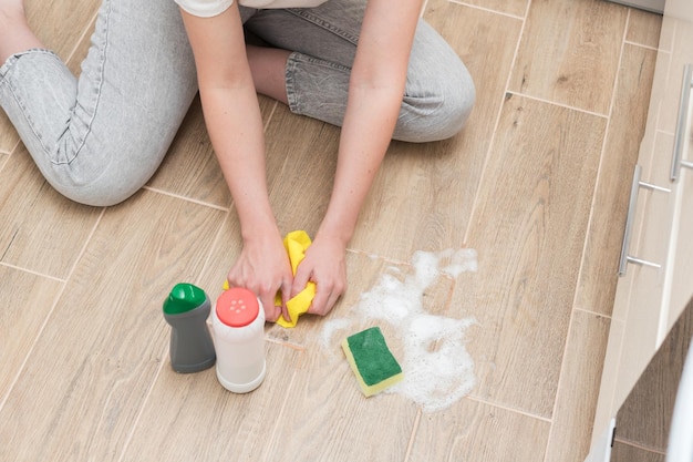 Woman washes the parquet with detergents with a washcloth and foam house cleaning closeup