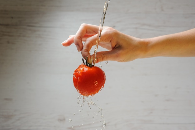 Woman washes a tomato