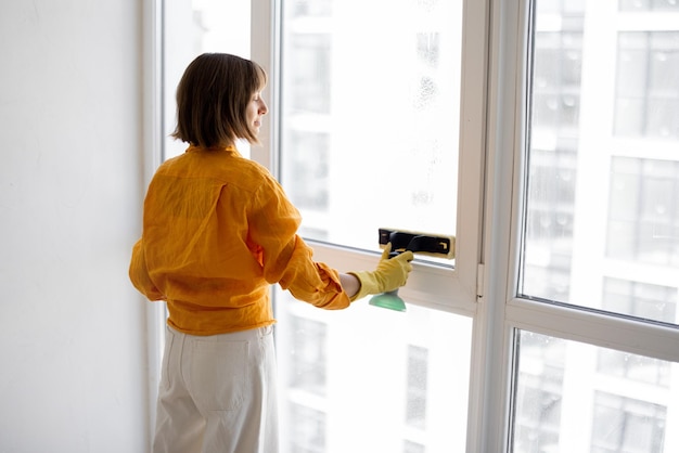 Woman washes window in apartment