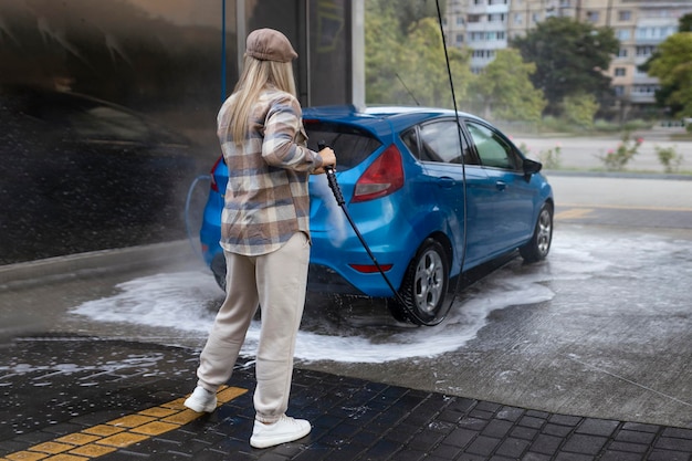 Woman washing a car in a selfservice car wash station with wahing foam Wash car selfservice station