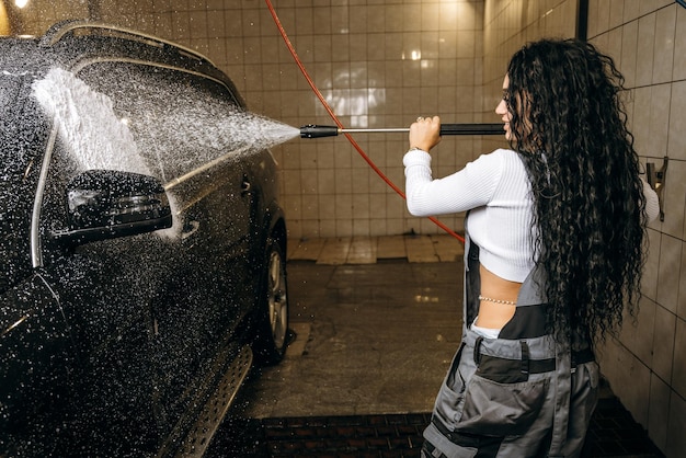 A woman washing a car with a hose