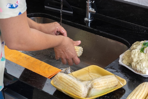 woman washing corn, preparing for dinner, brazilian dinner